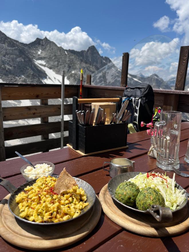 Kasspatzln and spinach Knödel on the hut terrace with the peaks behind