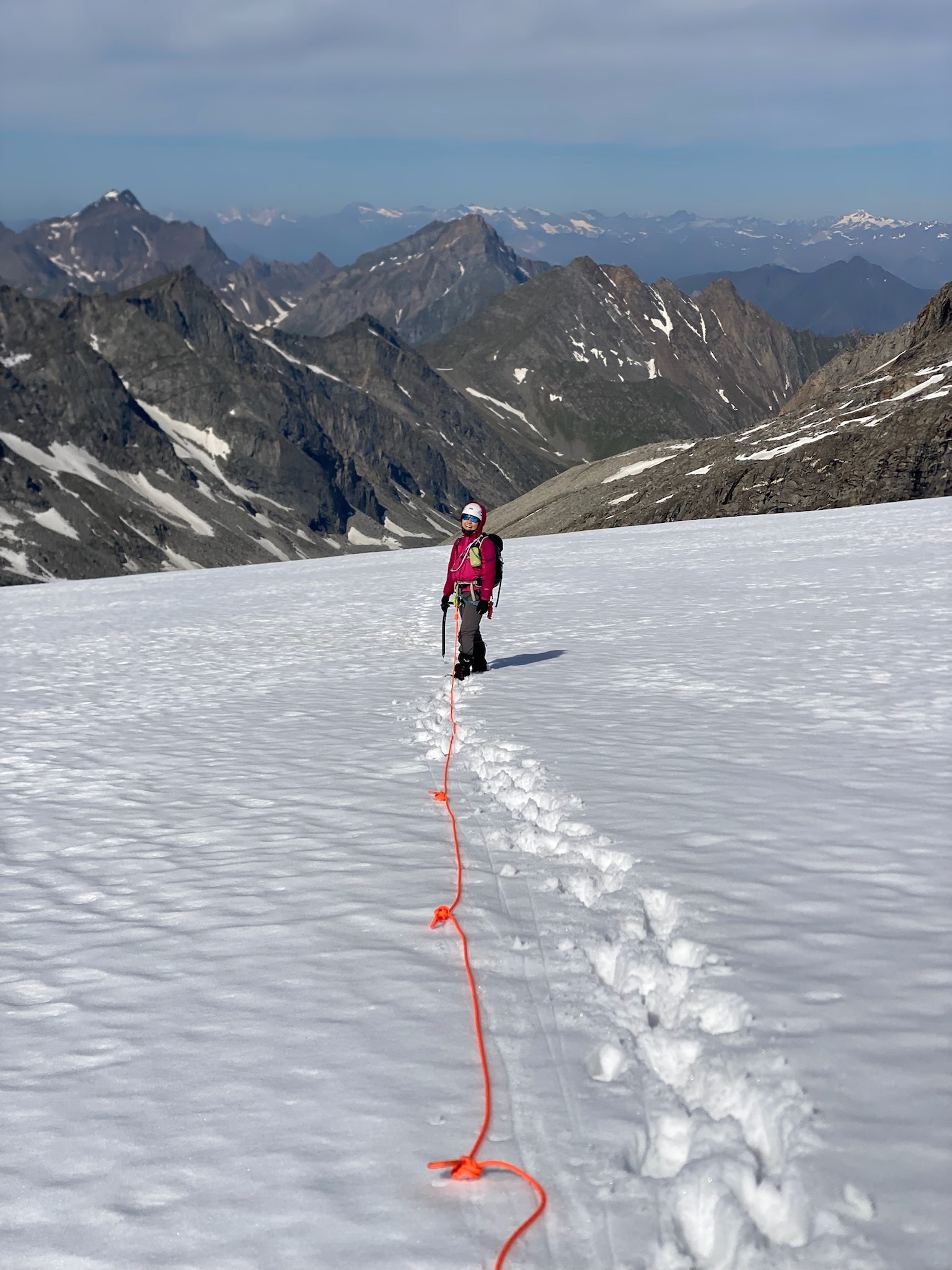 Roped up crossing the glacier with the mountain panorama behind