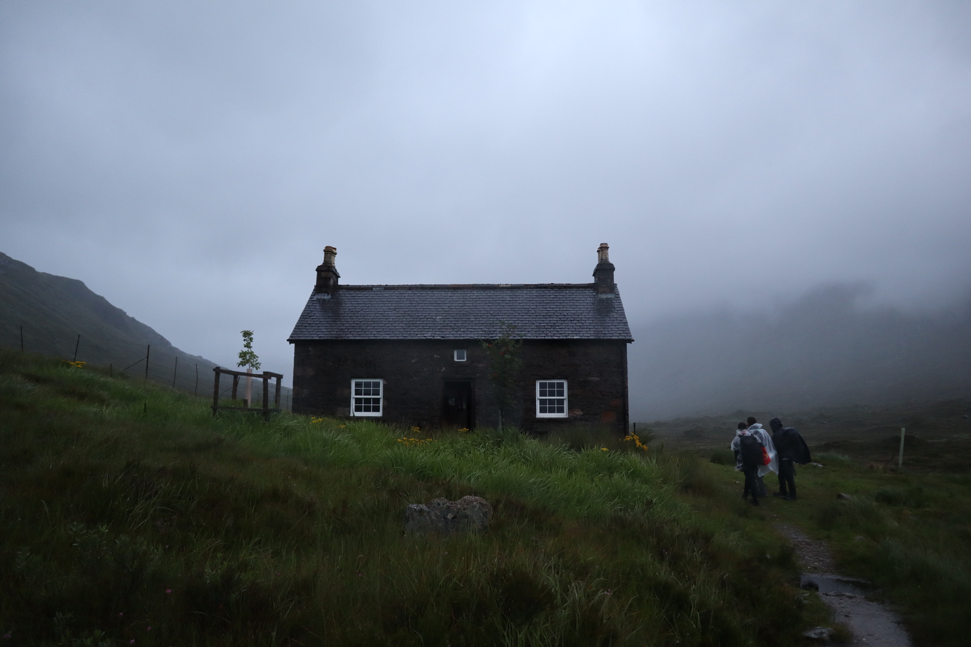 A stone bothy with two chimneys emerging out of highland mist