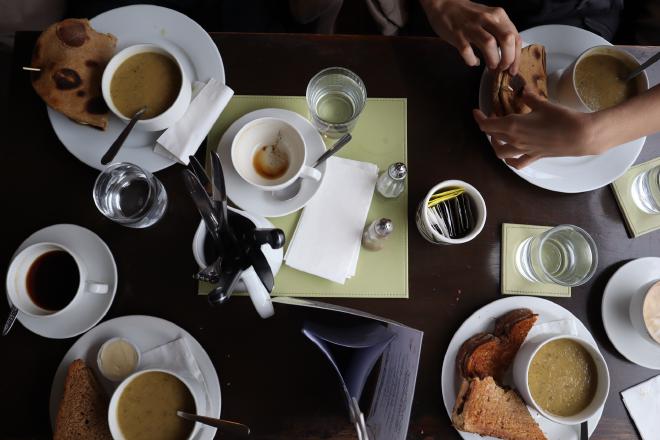 Table full of soup, bread and coffee cups seen from directly above