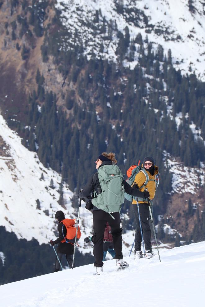 group ascending steep snowy slope with forest