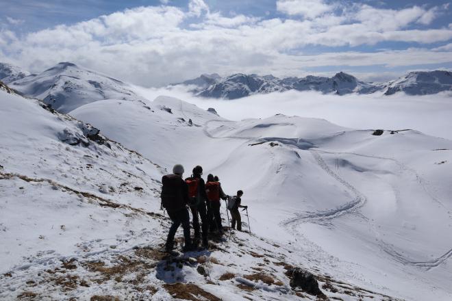 group overlooking snowy valley and sea of clouds