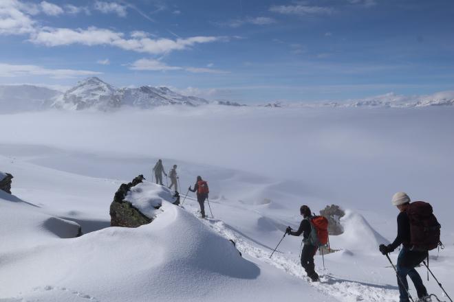 hikers descending ridge above sea of clouds
