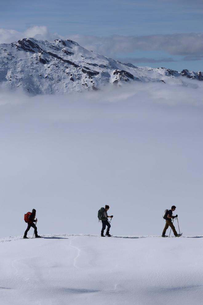 three hikers on narrow ridge with steep drop