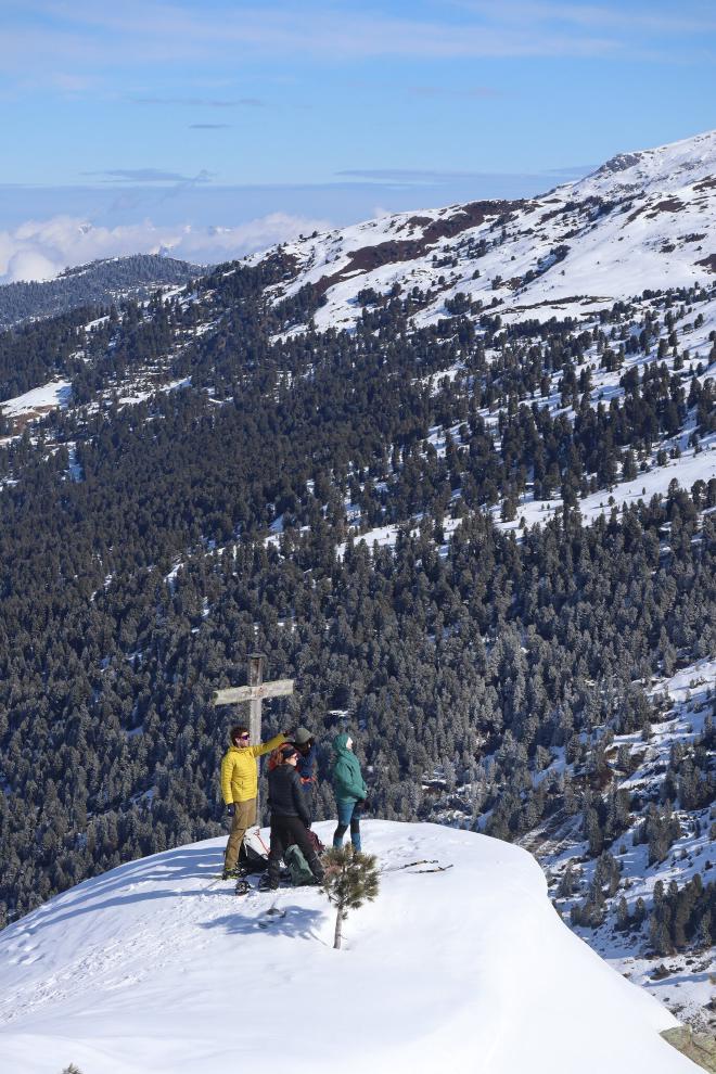 two hikers at summit cross with forest valley below