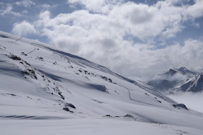 wide snow slopes with dramatic clouds and mountain