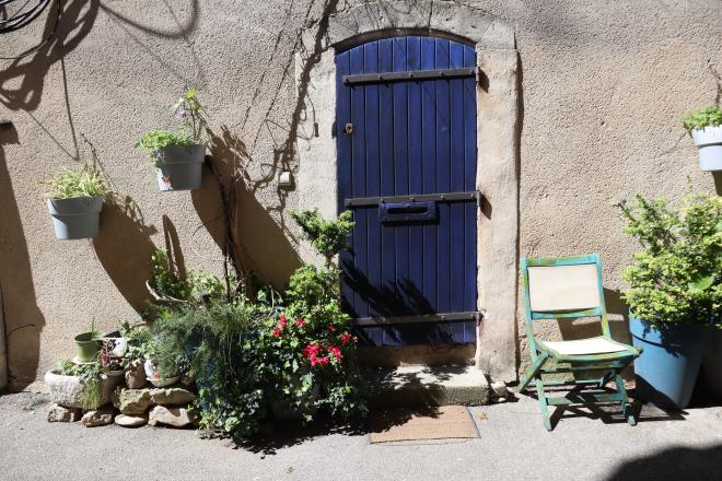 Blue door with flower pots on a stone wall in Provence